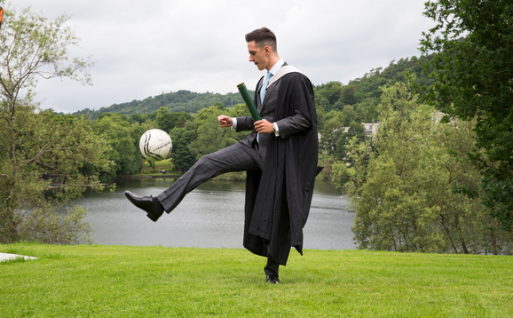 Student at graduation with football