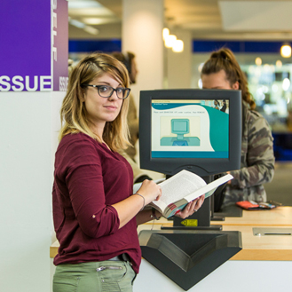 student in library at self service machine