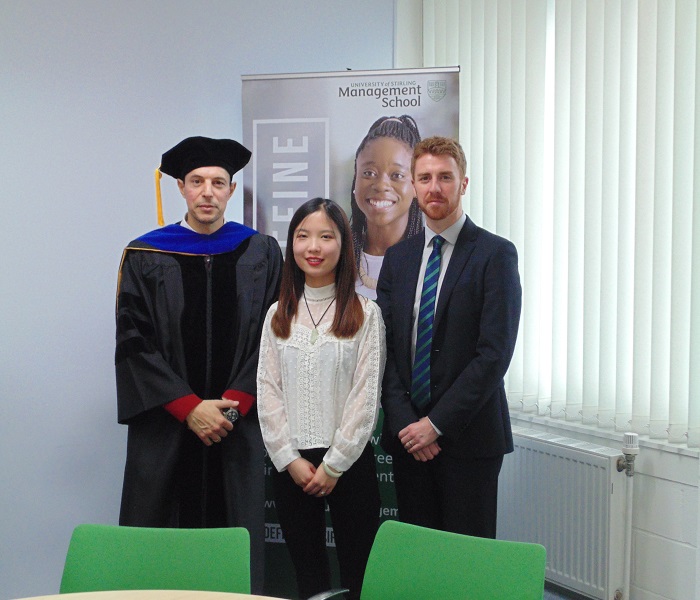 Academic in graduation robes with Chinese woman and German man