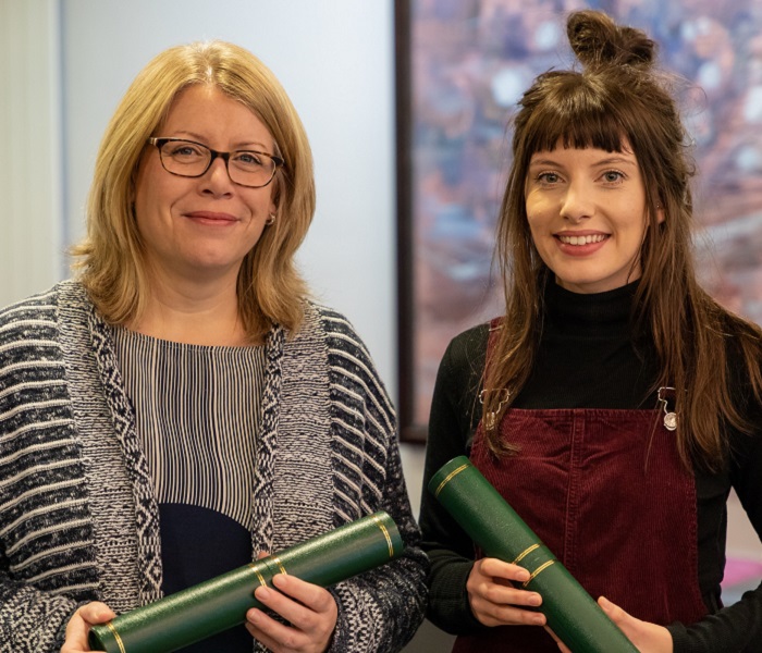 two women holding university scrolls