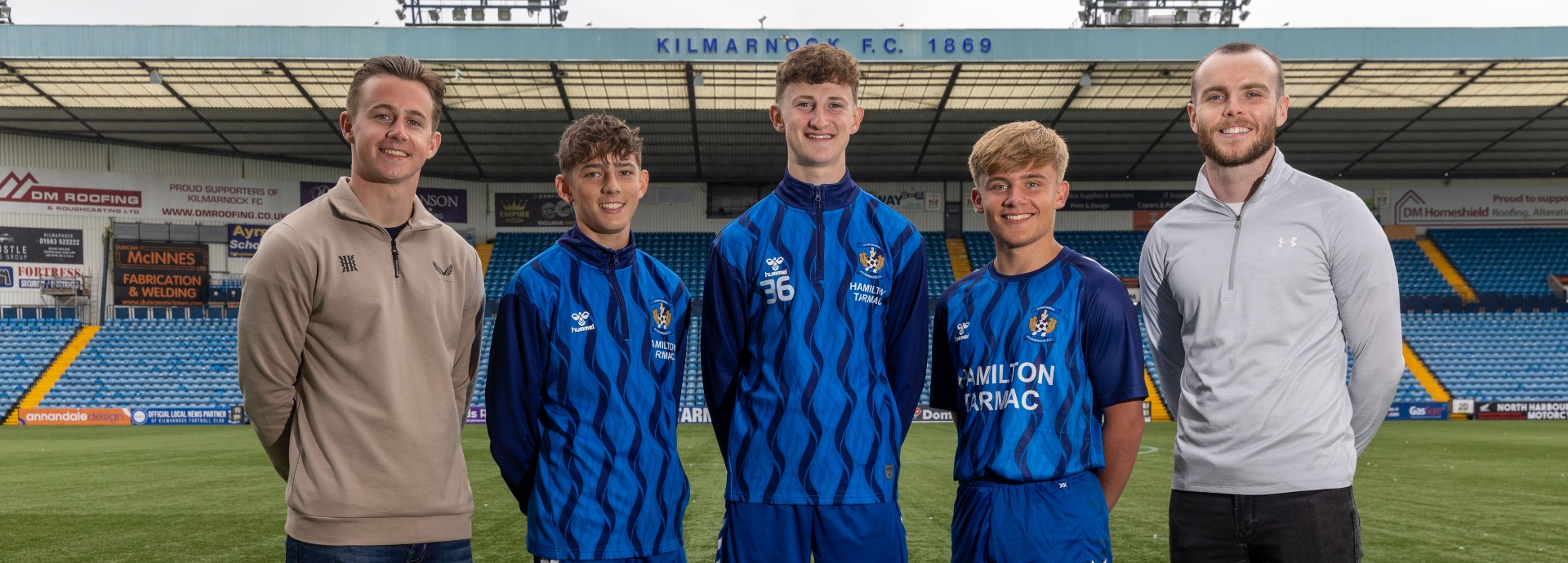Wellbeing Coaches Bradley Fullarton and Louis Kerr on the pitch at Kilmarnock Football Club with under-18s players Josh, Logan and Charlie