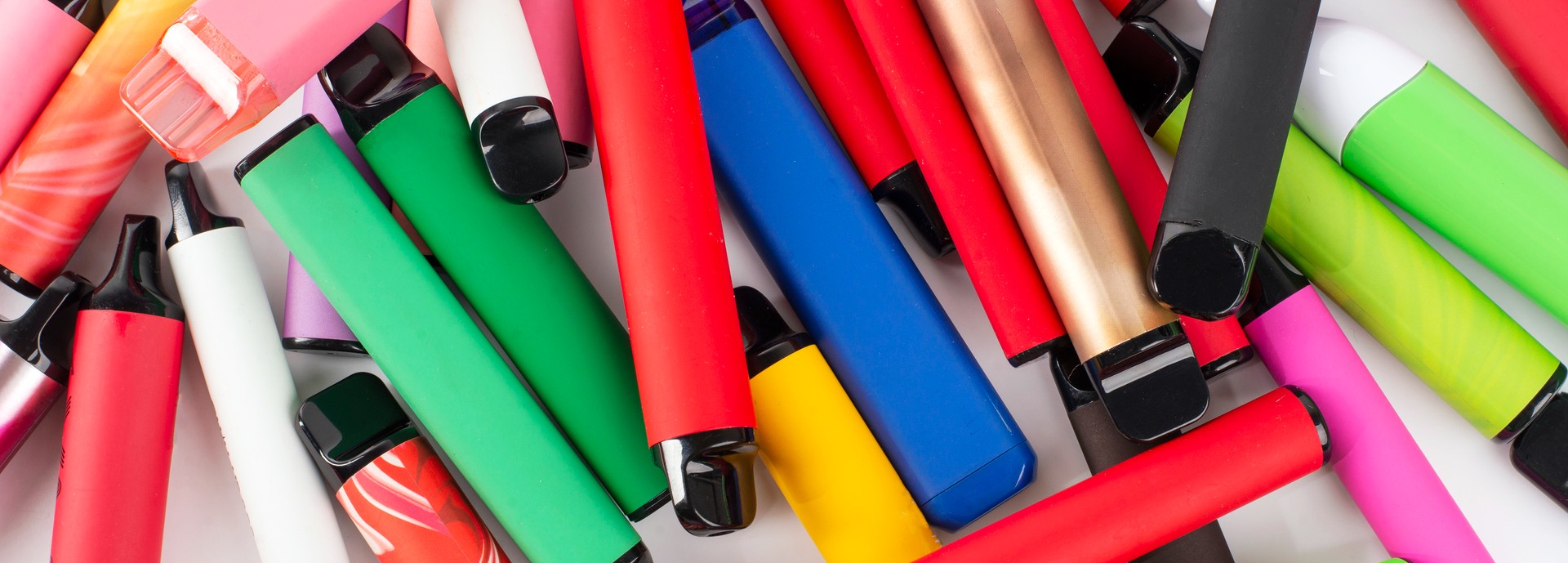 A pile of brightly coloured e-cigarettes scattered across a surface