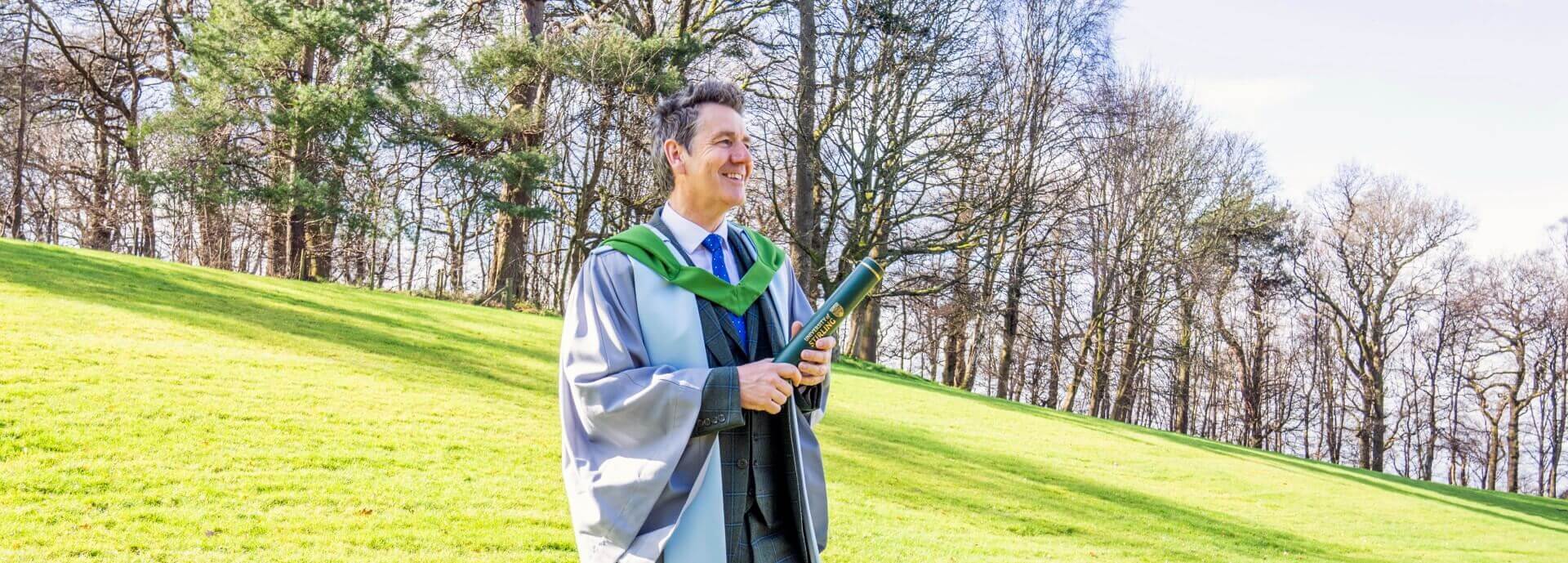 Dougie Vipond poses with his degree on the University of Stirling campus.