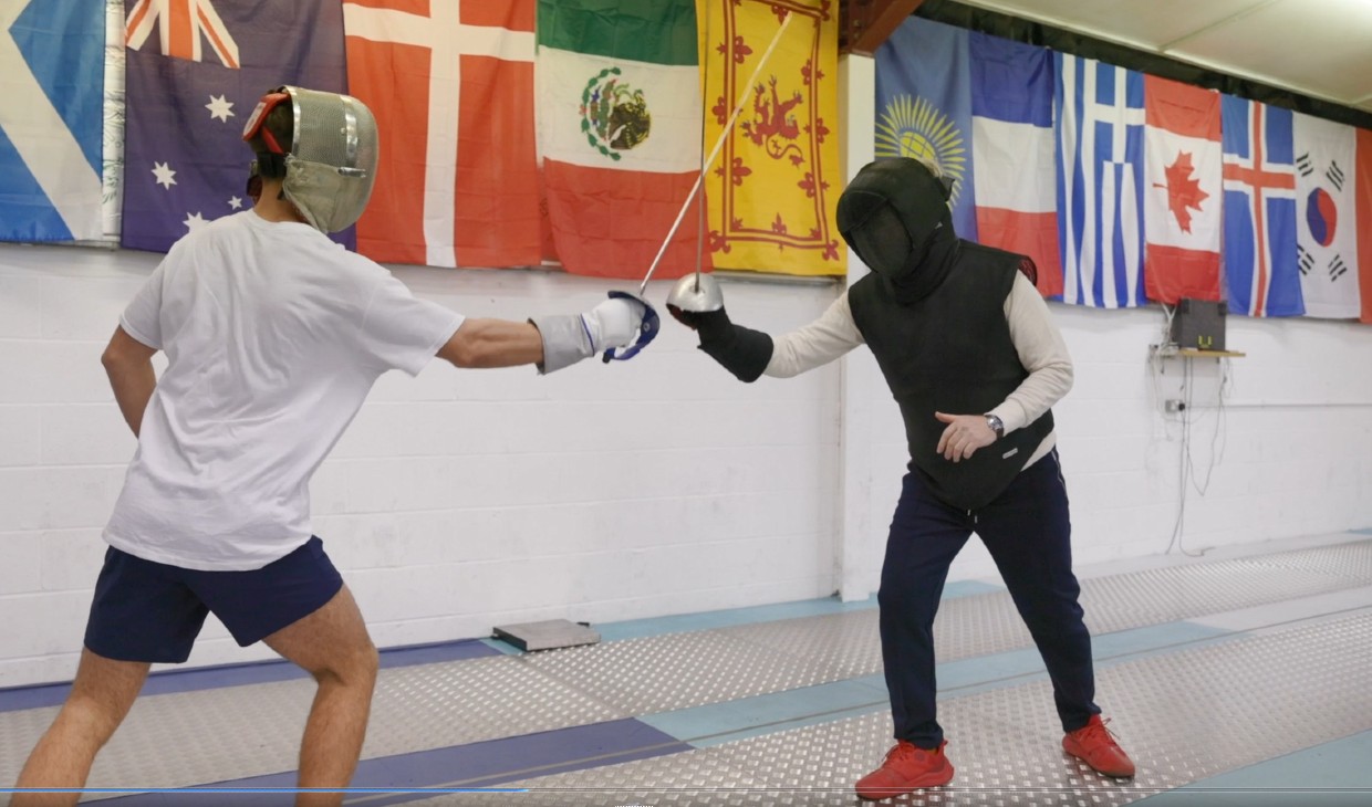 Two fencers training on mat