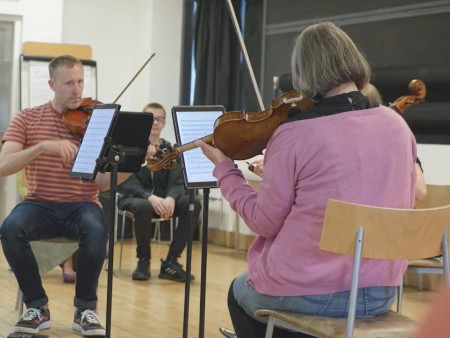 Two violinists perform to a group of young people