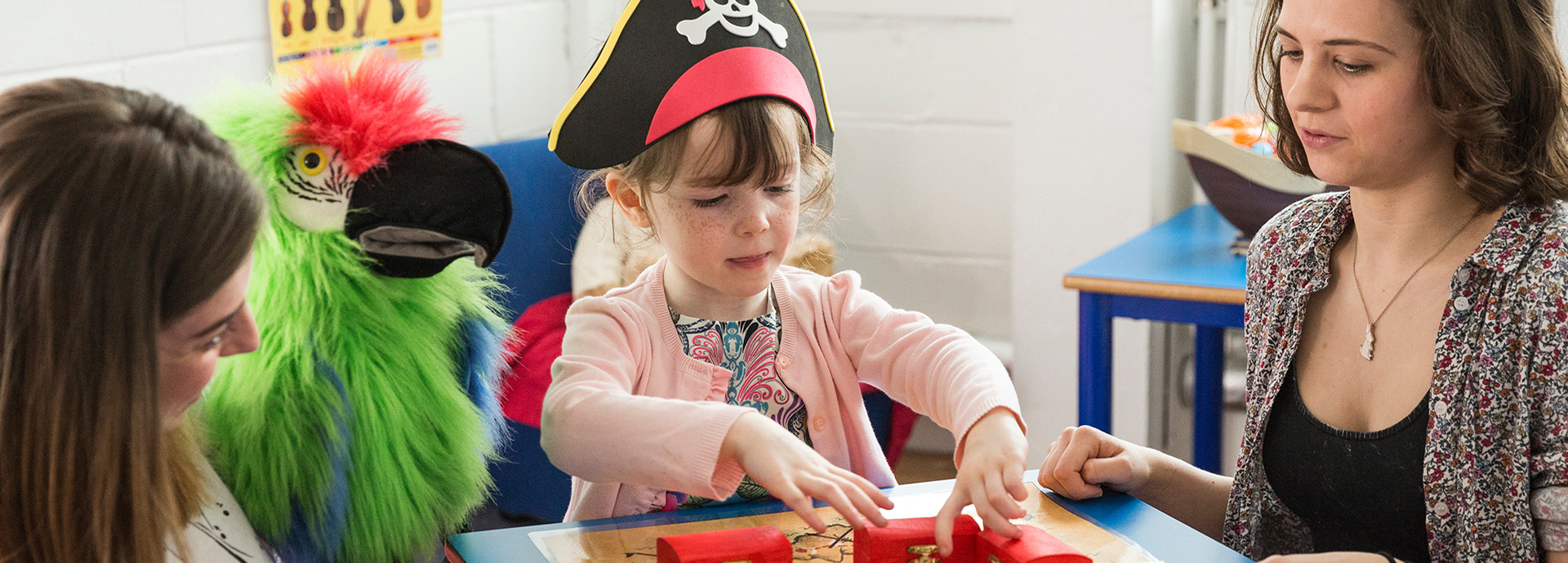 Two researchers, one with toy parrot, and child with pirate hat run an experiment